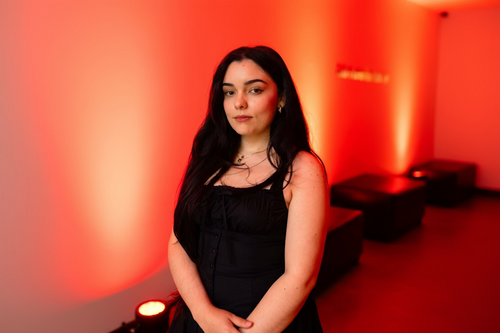 Woman in a black dress standing against a red background