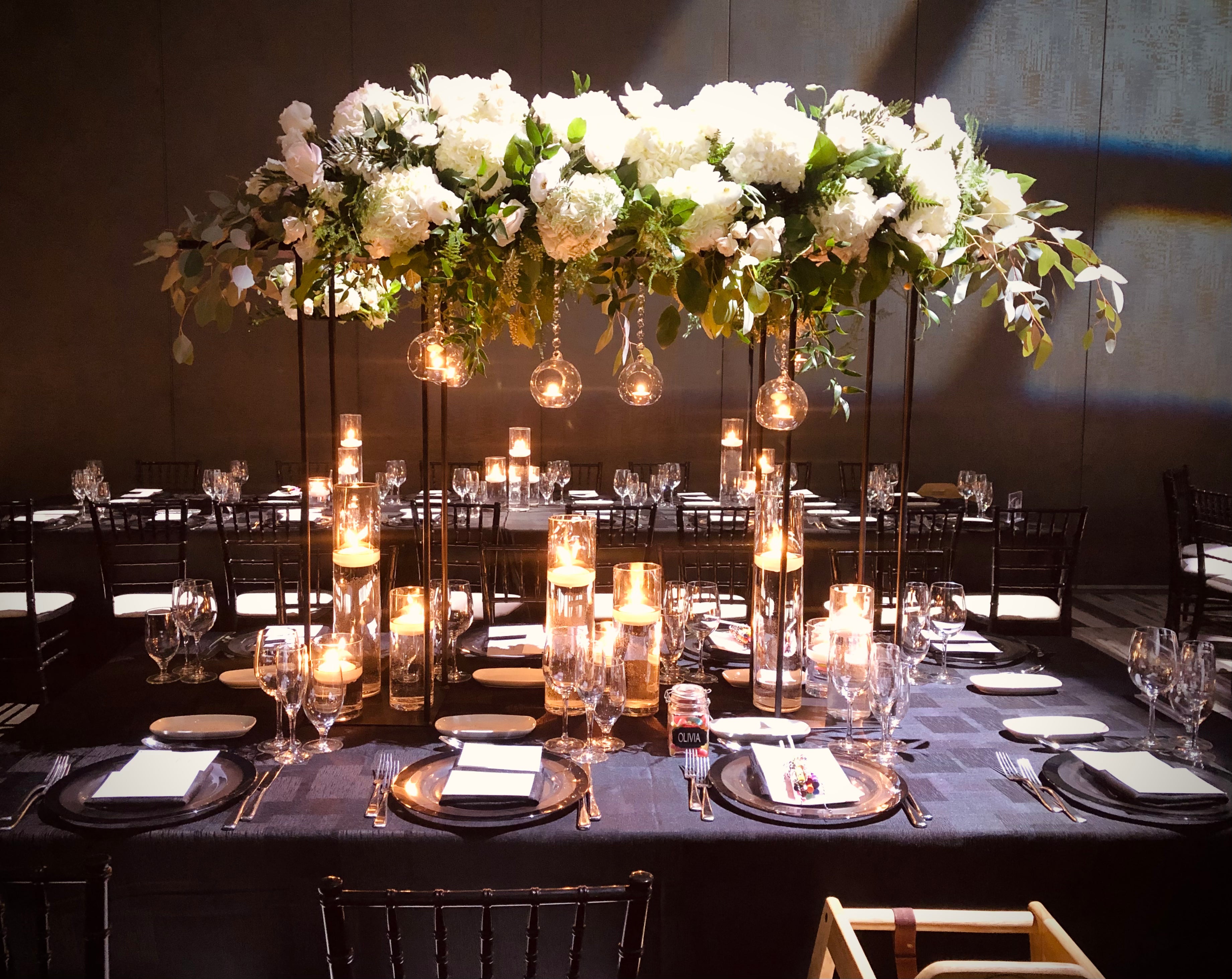 Decorated table setting with floral arrangements and candles in a formal event setup.