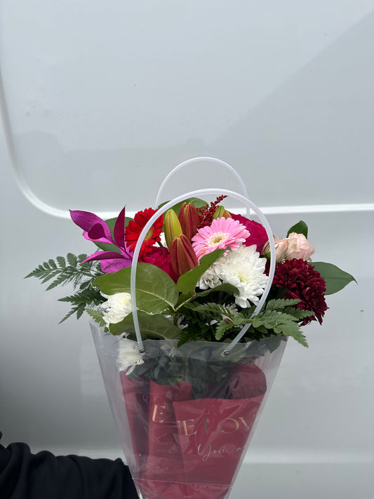 Bouquet of flowers in a clear vase with a red ribbon on a white background