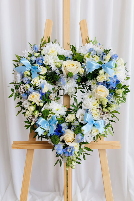 Floral wreath with blue and white flowers on a wooden surface